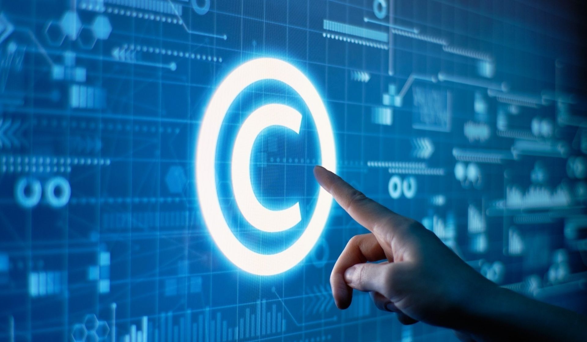 Image showing a blue digital interface with data and technological icons. A hand is pointing at a large glowing © (copyright) symbol, representing centralized management of intellectual property rights.